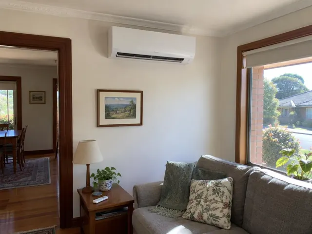 Split system mounted high on a living room wall above a sofa, with louvre open in Tea Tree Gully