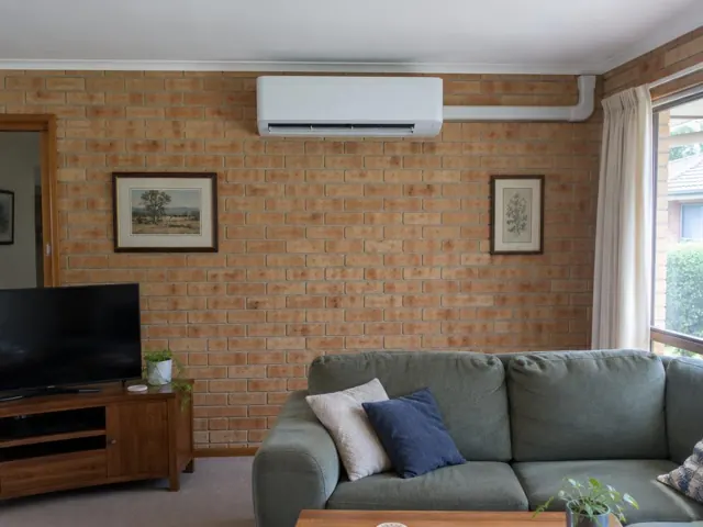 Split system indoor unit on a brick living room wall above a sofa in Modbury